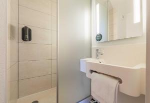 a white bathroom with a sink and a shower at B&B HOTEL Colmar Expo in Colmar