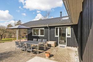 a black house with a table and chairs and an umbrella at 8302-Kolind-Falkevej-34 in Kolind
