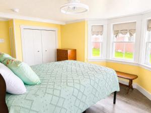 a bedroom with a bed and a bench and windows at Whimsea Cottage in Twillingate
