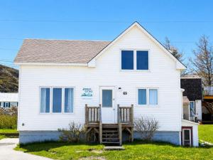 a white house with two chairs in front of it at Whimsea Cottage in Twillingate