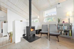 a fireplace in a living room with two chairs and a stove at 84174-Knebel-Fuglsovig-301 in Knebel