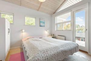a bedroom with a bed in a room with windows at 84174-Knebel-Fuglsovig-301 in Knebel