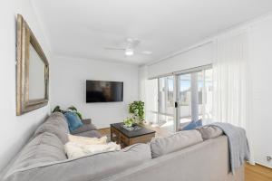 a white living room with a couch and a window at Riverfront on The Esplanade 3BDR in Perth