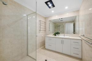 a bathroom with a shower and a sink and a mirror at Riverfront on The Esplanade 3BDR in Perth +20 photos