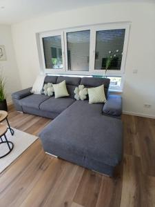 a living room with a blue couch and two windows at Ferienwohnung Skulpturenweg in Ludwigswinkel