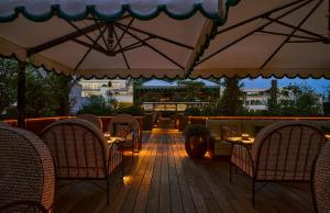 a patio with chairs and tables and an umbrella at Hôtel Fouquet's Paris in Paris