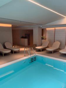 a pool in a hotel room with chairs and tables at Atlas Aparthotel & Spa in Piatra Neamţ