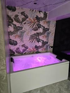 a purple bath tub with a wallpaper with birds on it at hotel v heritage in Surat