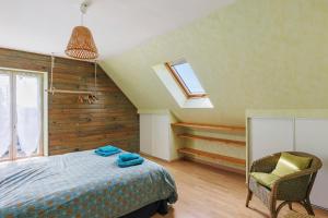 a bedroom with a bed and a window and a chair at Le Café de l'Encloître in Beaumont-la-Ronce