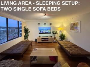 a living area sleeping setup with two single sofa beds at Canberra City View Apartment in Canberra