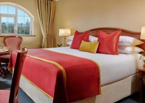 a hotel room with a large bed with red and yellow pillows at Killarney Towers Hotel & Leisure Centre in Killarney +20 photos