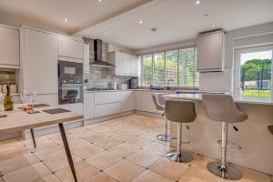a kitchen with white cabinets and a table and chairs at Finest Retreats - Dockyard House in Pembroke Dock