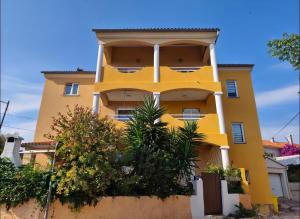a yellow building with trees in front of it at Apartman Ariana in Ližnjan