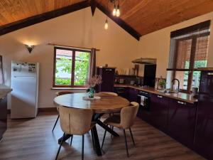 a kitchen with a wooden table and a wooden ceiling at Les Vergers d'Epona "Fremifontaine VOSGES" in Frémifontaine