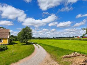 a dirt road through a field with a house at The Colored Butterfly in Månstad