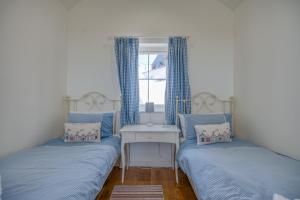 two beds in a small room with a window at Hafod in Tenby