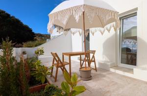 a patio with a table and chairs and an umbrella at OKTO Beach Loft in Praia do Almoxarife