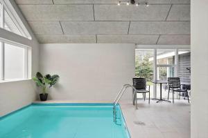 a swimming pool in a room with a table and chairs at M191-Vaeggerlose-Baeverstien-46 in Bøtø By