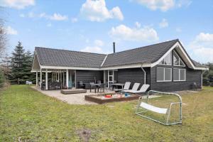 a black house with a patio and chairs in the yard at M191-Vaeggerlose-Baeverstien-46 in Bøtø By