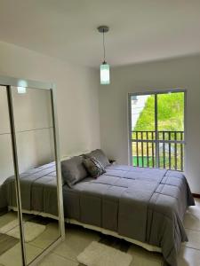 a bedroom with a bed and a large window at Apartamento Icônico em Petrópolis in Petrópolis