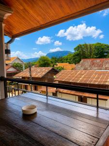 a wooden table on a balcony with a view of roofs at Ban Loom Guesthouse & Weaving Workshop in Luang Prabang