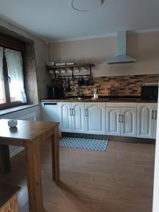a kitchen with white cabinets and a wooden table at La casina de isa in Aller +5 photos
