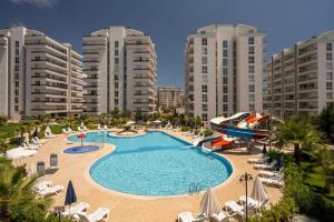 a large swimming pool with chairs and umbrellas and buildings at ARCADIA Homes in Alanya