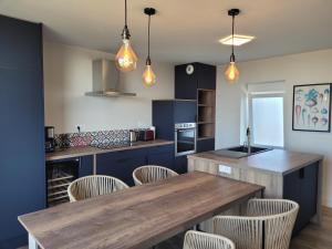 a kitchen with blue cabinets and a wooden table at Villa les pepouzes - vue mer - jacuzzi- sauna in Plouescat +26 photos