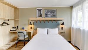 a hotel room with a large bed and a desk at Campanile NATURE - Moulins Avermes in Avermes