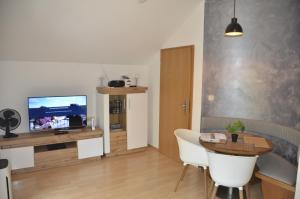 a living room with a television and a table and chairs at Ferienwohnung Wildgatter in Grafenwiesen