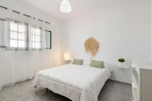 a white bedroom with a white bed with green pillows at Uga La Dehesa I in Uga