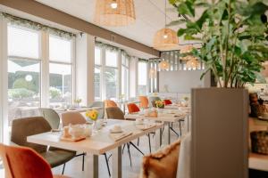 a dining room with tables and chairs and windows at Parkhotel Papenburg by Hackmann in Papenburg