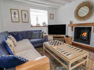 a living room with a blue couch and a fireplace at Tenandeleven Cottage in Denbigh