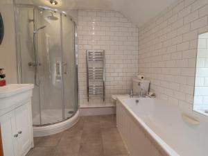 a bathroom with a tub and a shower and a sink at Tenandeleven Cottage in Denbigh +50 photos
