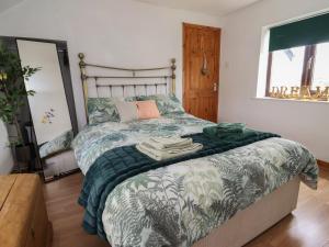 a bedroom with a large bed with a blanket on it at Tenandeleven Cottage in Denbigh