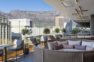 a balcony with tables and chairs and a view of mountains at Radisson Hotel Cape Town Foreshore in Cape Town +132 photos