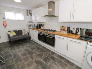 a kitchen with white cabinets and a stove top oven at Lodge Park in Corby +12 photos