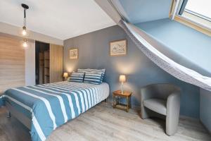 a bed and a chair in a room with a staircase at Chambres D'hôtes - Les Vergers in Muneville-sur-Mer
