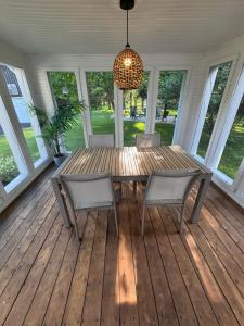 a wooden table and chairs on a porch with a chandelier at Le Pimbina in Mont-Tremblant