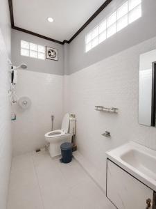 a white bathroom with a toilet and a sink at Ban Loom Guesthouse & Weaving Workshop in Luang Prabang +32 photos