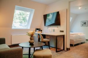a living room with a desk and a couch at Parkhotel Papenburg by Hackmann in Papenburg +56 photos