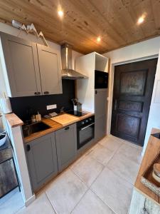 a kitchen with white cabinets and a wooden ceiling at charmant studio à Morzine avec piscine privé in Morzine +4 photos
