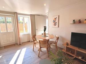 a living room with a table and a television at Les Terres Beaujolaises in Belleville-en-Beaujolais