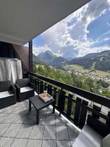 a balcony with a table and chairs and mountains at charmant studio à Morzine avec piscine privé in Morzine