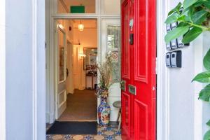 a red door leading into a hallway with a vase at GuestReady - Links View in Edinburgh