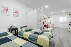 two beds in a room with white walls and wooden floors at Studio 1 Soto Parking Renfe in Torrejón de Ardoz