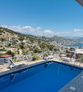 a pool with chairs and a view of a city at Vitamin Sea in Sarandë