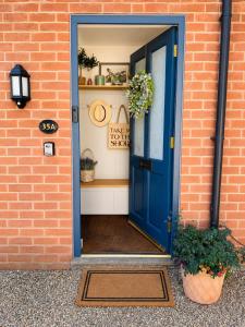 a blue door on a brick building with plants at Urban Stay Apartment in Aylsham