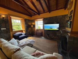 a living room with a couch and a flat screen tv at Casa da Terra Alta in Santo Amaro