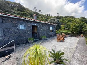 a stone house with a patio with tables and benches at Casa da Terra Alta in Santo Amaro